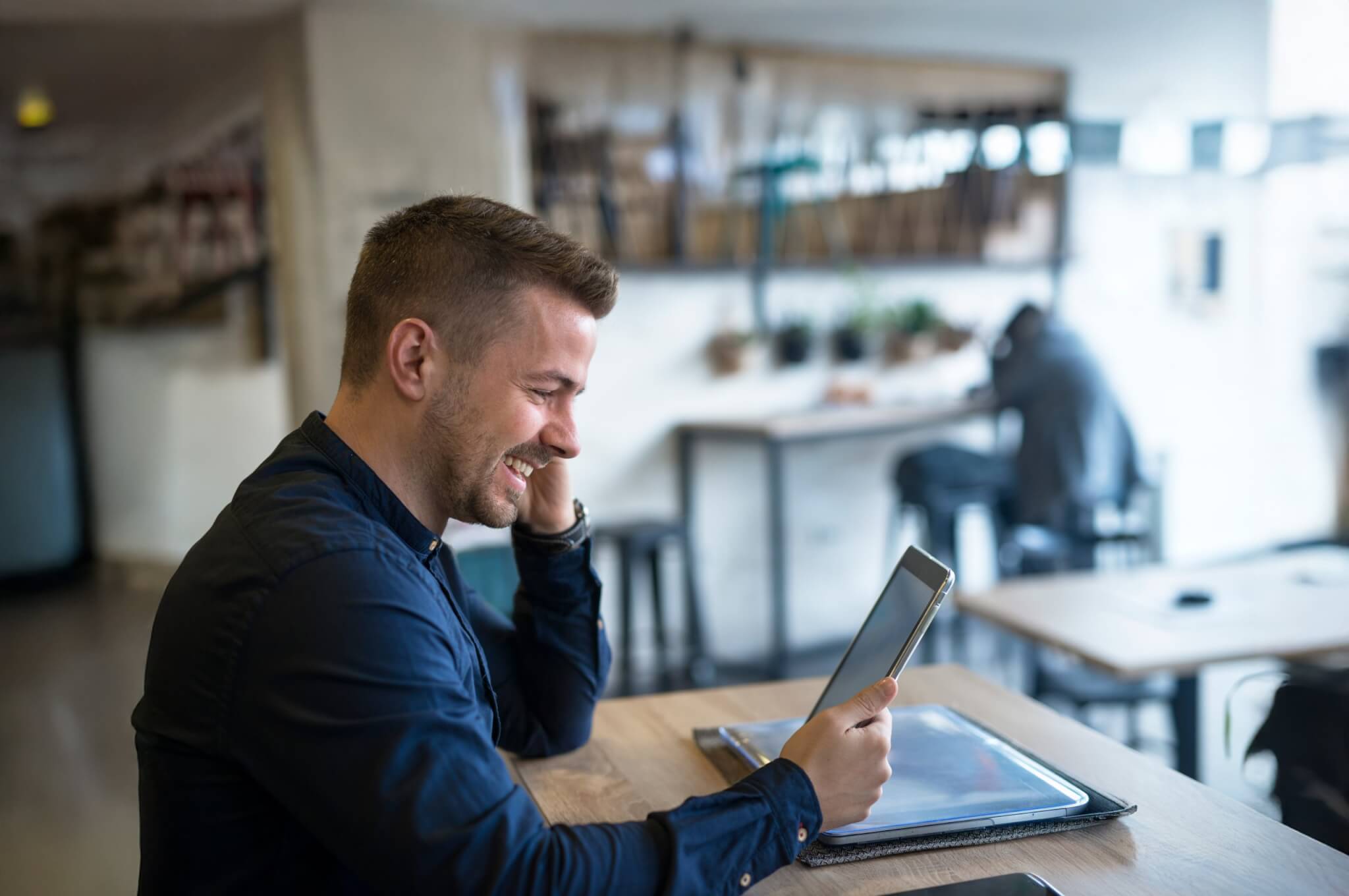 successful-businessman-with-headphones-using-tablet-cafe-bar-2